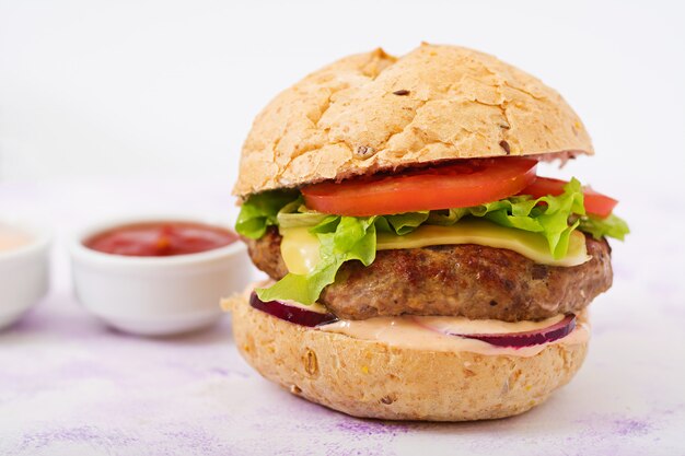 Grand sandwich - hamburger avec burger de boeuf juteux, fromage, tomate, oignon rouge et frites.