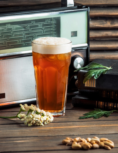 Un grand verre de bière et de cacahuètes salées.