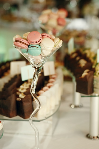 Photo gratuite grand verre à cocktail avec des macarons sur la table du dîner