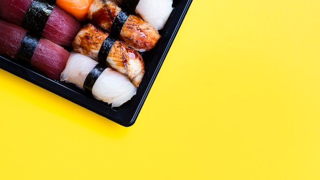 Grande assiette de sushi noir sur fond jaune