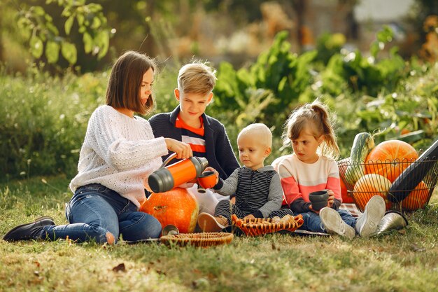 Grande famille assise sur un jardin près de nombreuses citrouilles