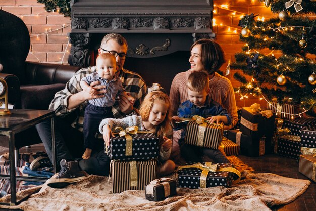 Grande famille la veille de Noël avec des cadeaux par l'arbre de Noël