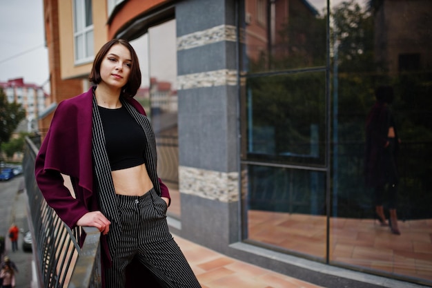 Une grande jeune femme modèle belle et élégante aux longues jambes au manteau bordeaux