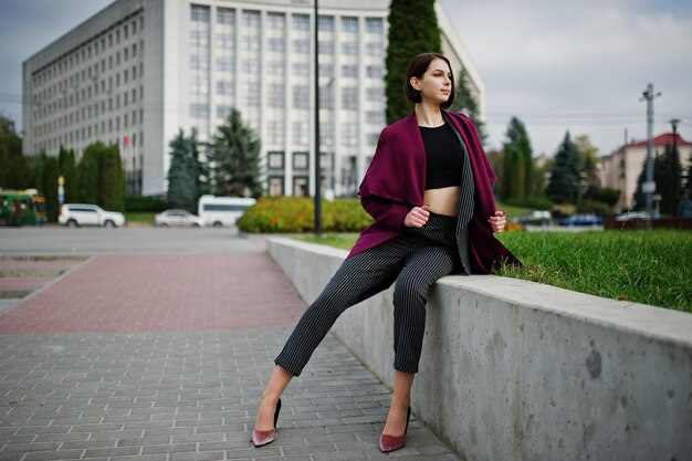 Une grande jeune femme modèle belle et élégante aux longues jambes au manteau bordeaux