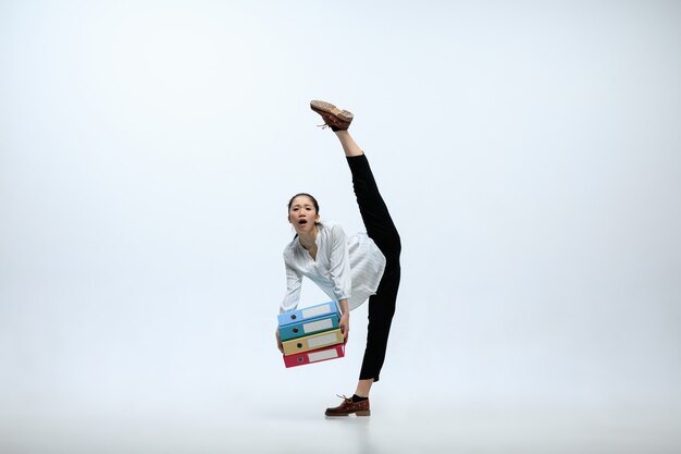 Grande responsabilité. Souffrant femme travaillant au bureau, sauter et danser dans des vêtements décontractés ou costume isolé sur fond de studio blanc. Entreprise, start-up, concept d'espace ouvert de travail.