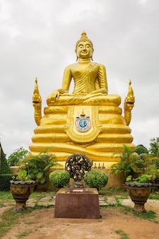 Grande statue de bouddha. statuette de couleur dorée. il y a de grands vases en pierre avec des fleurs autour. phuket, thaïlande