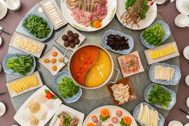 Grande table ronde avec différents plats d'accompagnement dessus avec soupe au milieu