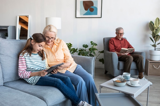 Grands-parents et fille avec ordinateur portable à l'intérieur