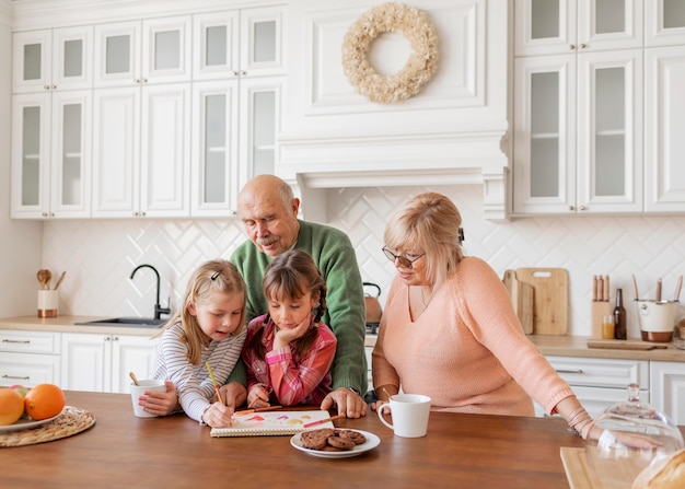 Grands-parents et filles à coup moyen dans la cuisine