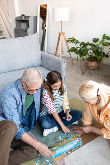 Grands-parents de tir moyen et enfant faisant puzzle