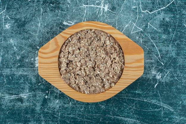 Granola bio fait maison dans une assiette en bois, sur fond bleu. photo de haute qualité