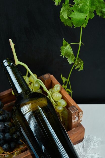 Une grappe de raisin et une bouteille de vin sur un tableau blanc, gros plan. Photo de haute qualité