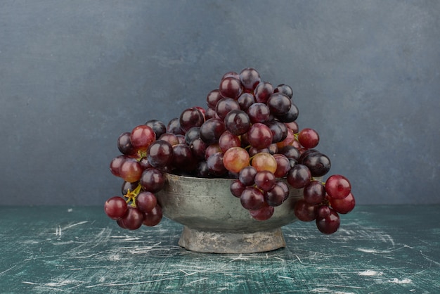 Une grappe de raisin noir dans le vase sur une table en marbre.