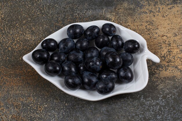 Grappe de raisin noir sur plaque en forme de feuille.