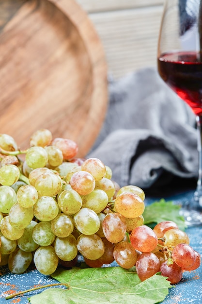 Grappe de raisin et un verre de vin sur fond bleu. Photo de haute qualité