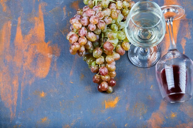 Grappe de raisin et verres de vin sur bleu.