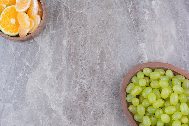 Grappe de raisin vert dans un bol en bois et d'agrumes.