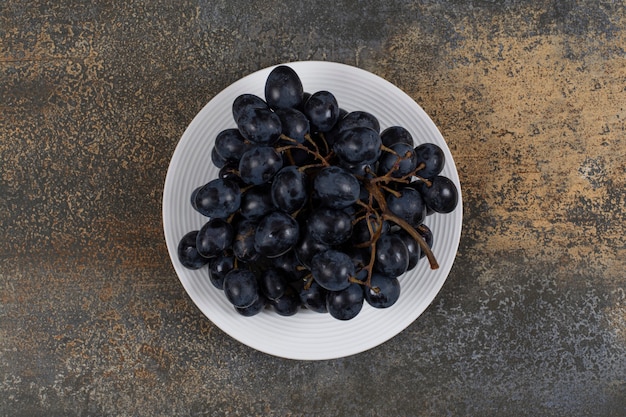 Grappe de raisins noirs sur plaque blanche.