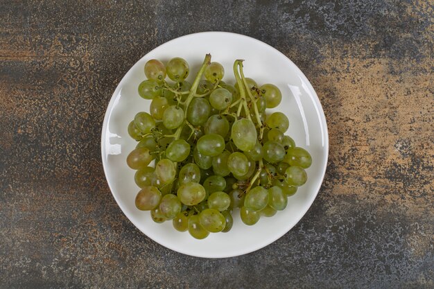 Grappe de raisins verts sur plaque blanche.