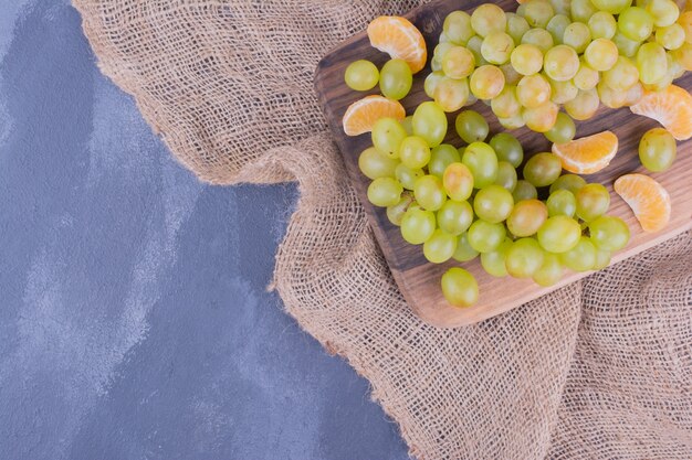 Grappes de raisin sur un plateau en bois avec des mandarines autour