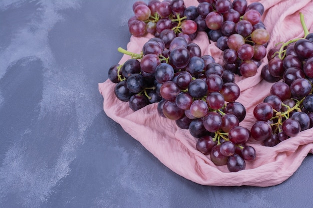 Grappes de raisin rouge sur un morceau de serviette rose.