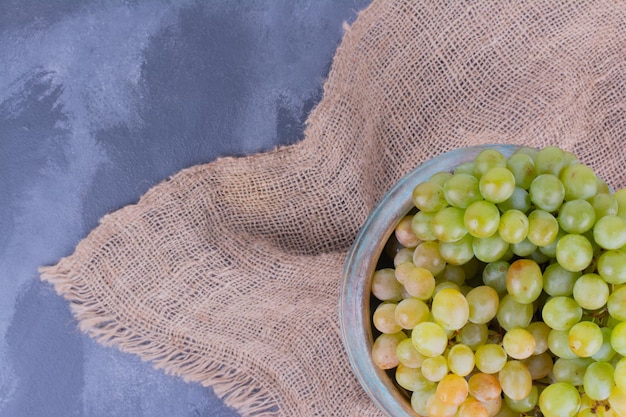 Photo gratuite grappes de raisin vert sur un morceau de toile de jute.