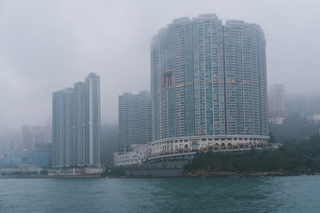 Photo gratuite gratte-ciel de béton gris sur la côte par temps de brouillard