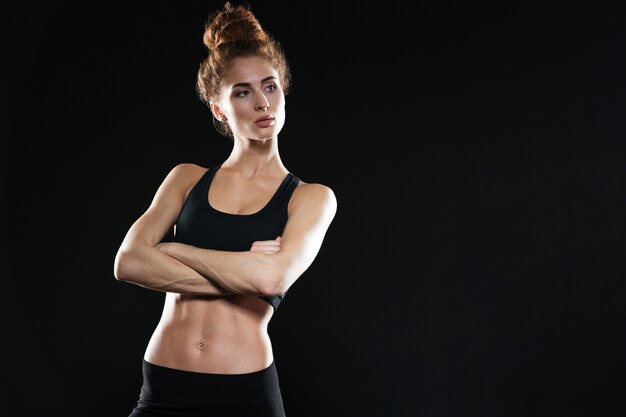 Grave jeune femme sportive posant avec les bras croisés