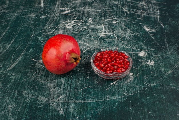 Grenade entière et graines sur table en marbre.