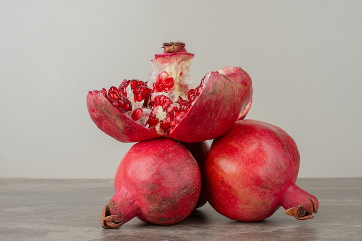 Photo gratuit grenades mûres et graines sur table en marbre.