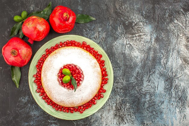 grenades rouges trois grenades avec des feuilles à côté du gâteau appétissant