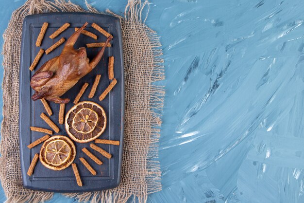 Grill, citron séché et croûtons sur un plateau sur la serviette en toile de jute , sur fond bleu.