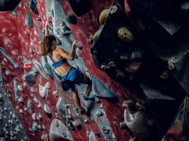 Grimpeuse professionnelle sur un mur de bloc à l'intérieur.