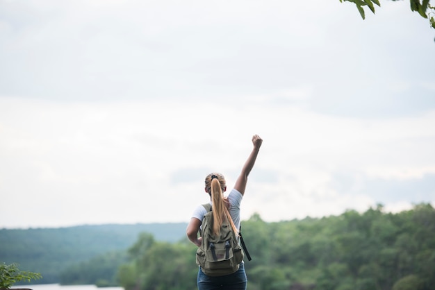 Gros dos de fille de touriste avec les bras levés heureux avec la nature près du lac. Concept de voyage.