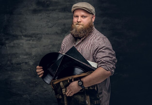 Gros hipster barbu tient des disques vinyles.