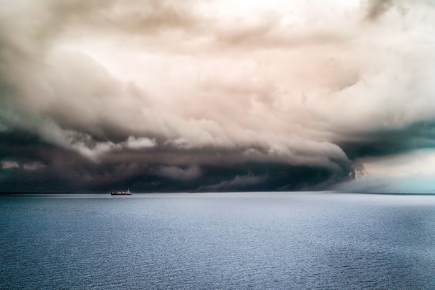 De gros nuages sombres couvrant l'océan pur avec un navire naviguant dedans