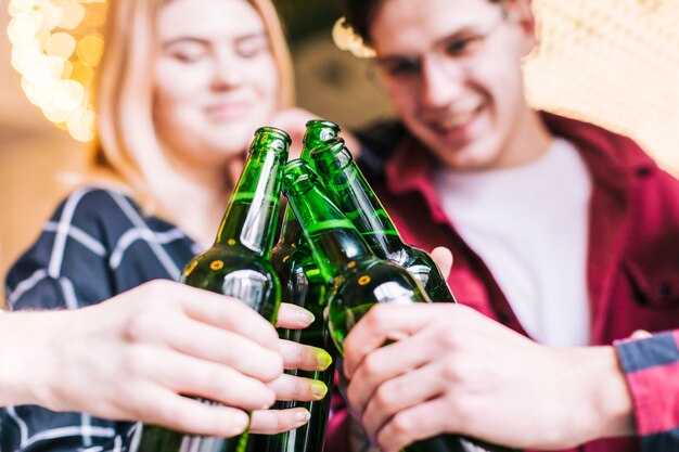 Gros plan, amis, grillage, bouteilles vertes, bière