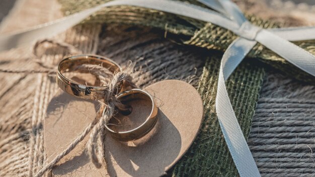 Gros plan des anneaux de mariage dorés attachés à un textile en forme de coeur marron