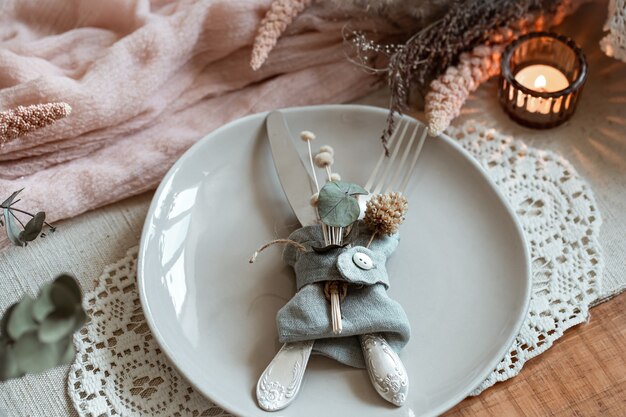 Gros plan d'une assiette avec des couverts, décorée de fleurs séchées.