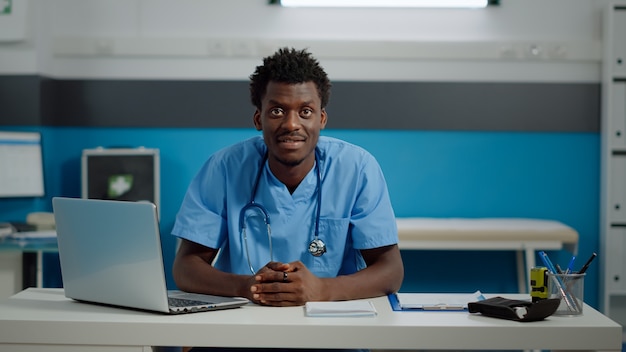 Gros plan d'un assistant médical noir souriant assis au bureau