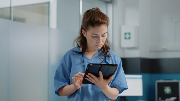 Gros plan d'un assistant médical regardant l'écran de la tablette avec des informations