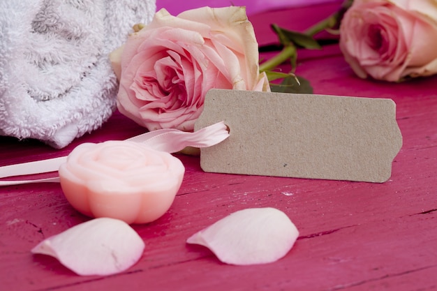 Gros plan d'une balise, de belles roses roses et une bougie sur une surface rose