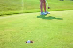 Photo gratuite gros plan d'une balle dans un trou sur un terrain de golf avec un joueur