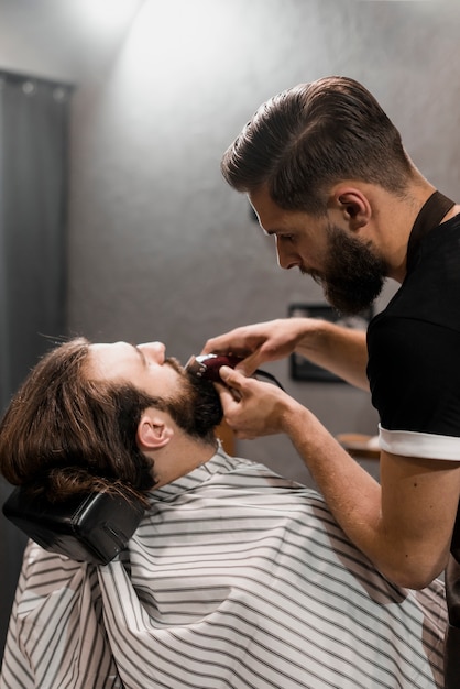 Gros plan, de, a, barbier, tailler, barbe, homme, à, électrique, tondeuse