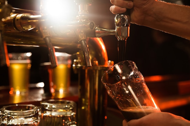 Gros plan d'un barman versant de la bière