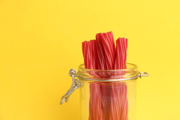 Gros plan de bâtons de réglisse rouge dans le pot sur fond jaune