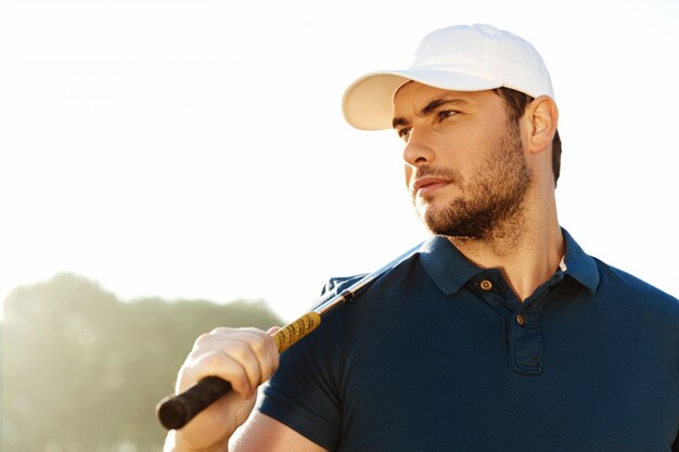 Gros plan d'un beau golfeur masculin tenant un club de golf