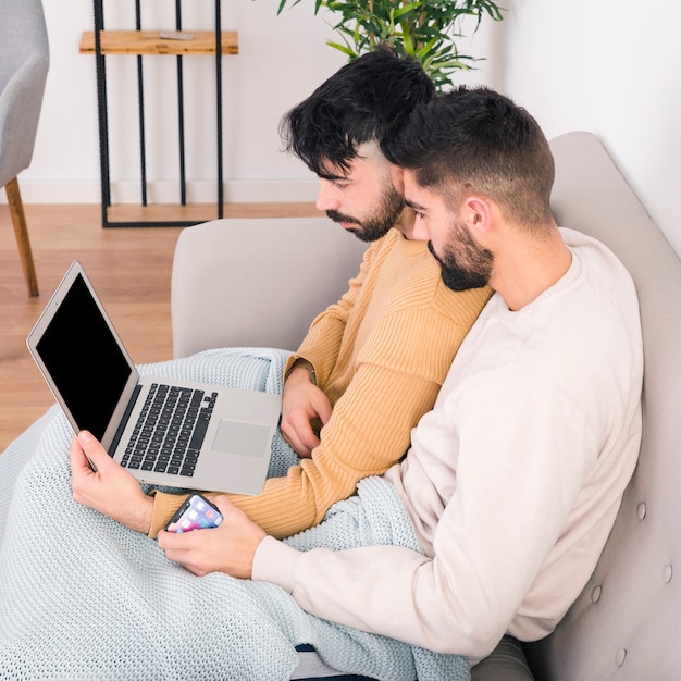 Photo gratuite gros plan, beau, jeune, gay, couple, séance, sofa, regarder, ordinateur portable, écran