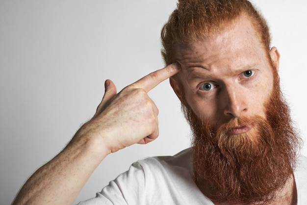 Photo gratuite gros plan d'un beau jeune homme aux cheveux roux européen avec des taches de rousseur et une barbe floue fronçant les sourcils, regardant la caméra avec colère ou indignation comme pour dire: êtes-vous fou. expressions faciales humaines