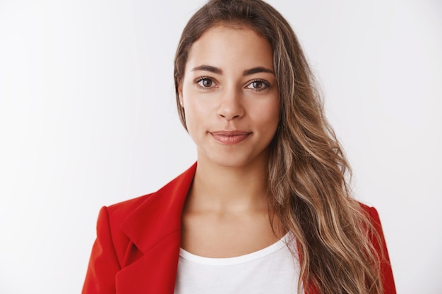 Gros plan beau souriant sympathique stagiaire féminin prêt à s'attaquer aux tâches souriant largement se sentant chanceux au travail, sûr de lui encouragé à réussir, objectif, mur blanc